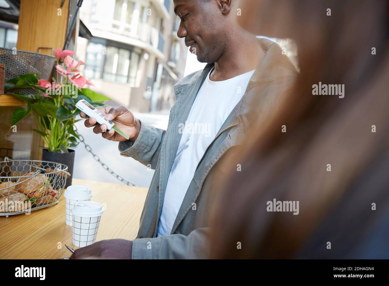 Uomo medio adulto che paga attraverso il lettore di carta di credito in concessione stand Foto Stock