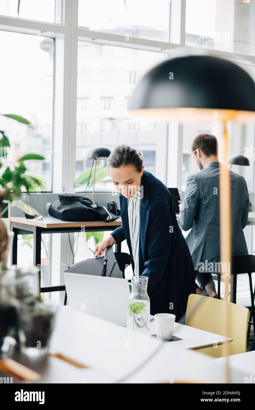 Donna d'affari che esamina il file mentre si trova alla caffetteria dell'ufficio della scrivania Foto Stock
