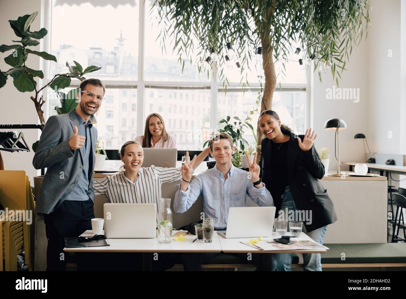 Ritratto dei colleghi sorridenti con i notebook che si accingono alla scrivania spazio di lavoro Foto Stock