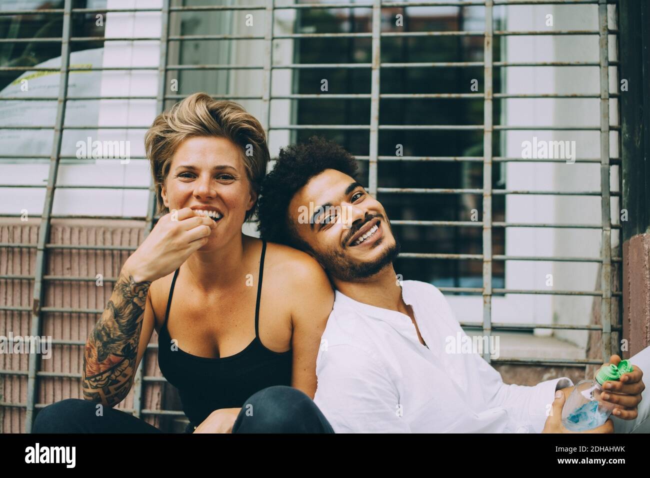 Ritratto di donna che mangia frutta mentre l'amico si appoggia su di lei contro il finestrino Foto Stock