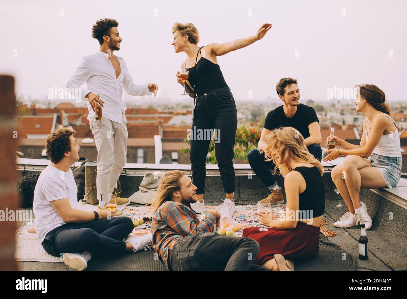 Buona gente che balla mentre si ascolta la musica con gli amici sulla terrazza al party sul tetto Foto Stock