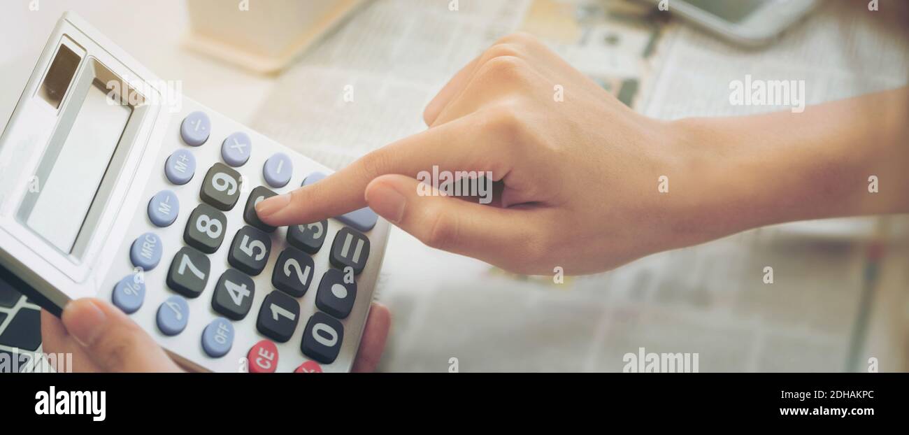 Donna contabile o lavoratore bancario utilizza la calcolatrice in ufficio per il conto profitti e perdite aziendali. Stile banner Web orizzontale. Foto Stock