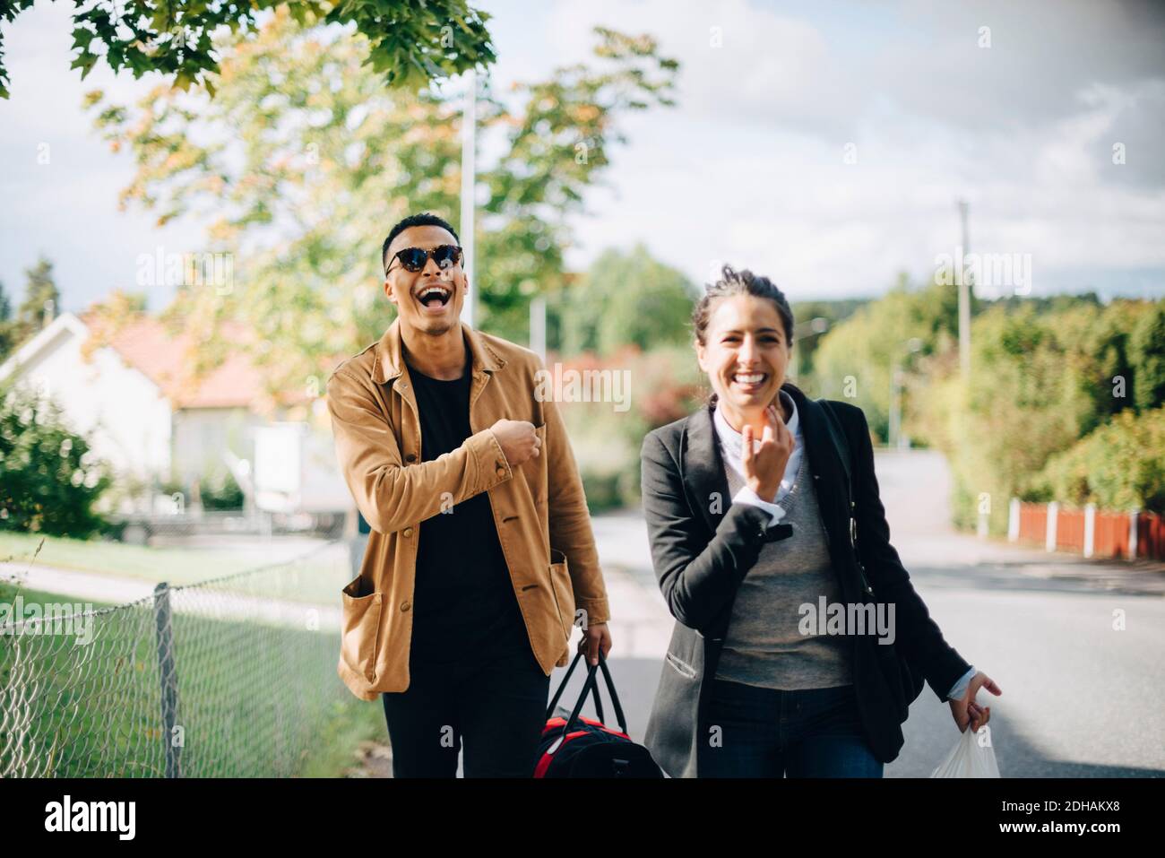 Amici felici che camminano sulla strada in città durante il giorno di sole Foto Stock