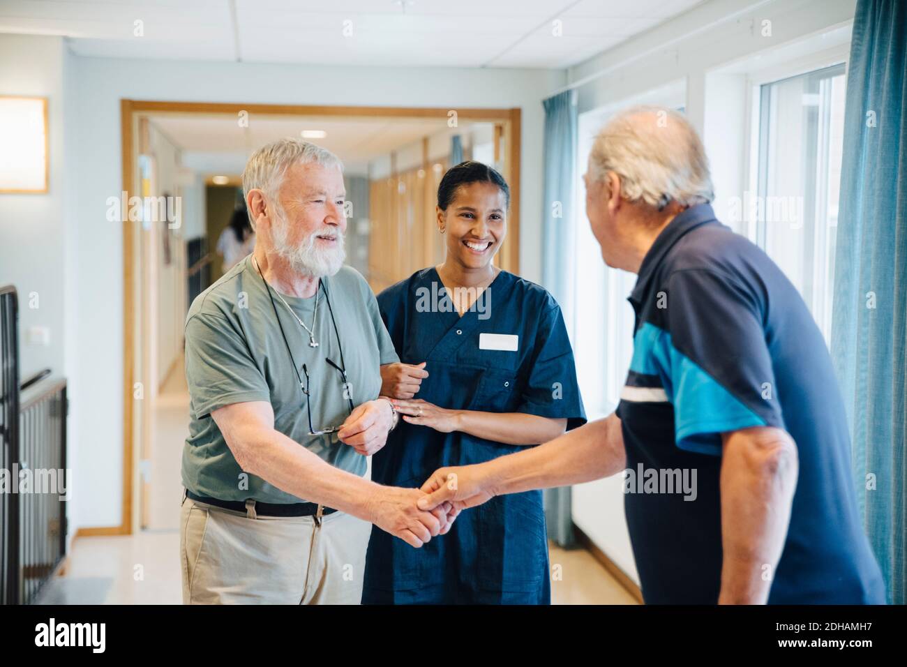 Braccio uomo anziano nel braccio con infermiere femminile durante la donazione amico handshake in vicolo a casa di cura Foto Stock