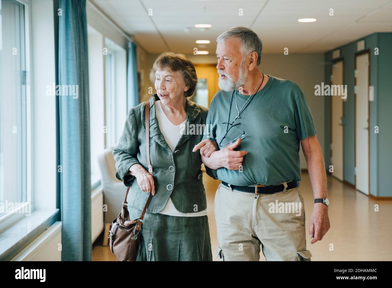 Coppia anziana che cammina braccio nel braccio a casa di cura anziana Foto Stock