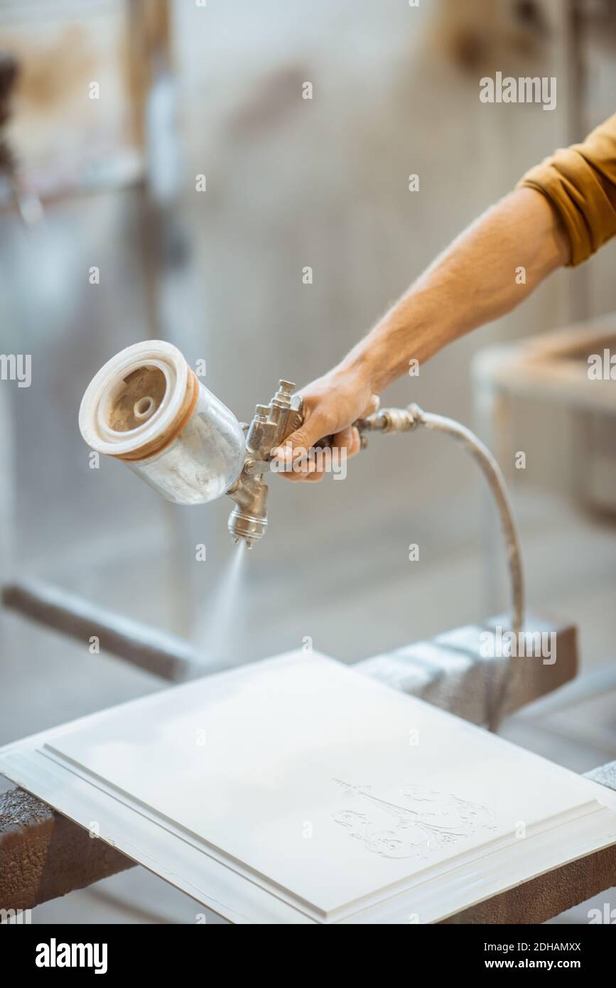 Verniciatura del prodotto in legno con una pistola a spruzzo presso il negozio di pittura della carpenteria, primo piano Foto Stock