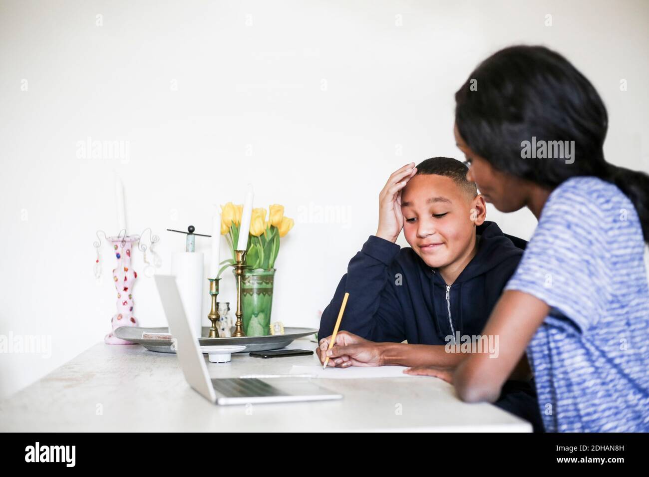 Madre aiutare figlio di fare i compiti al tavolo da pranzo Foto Stock