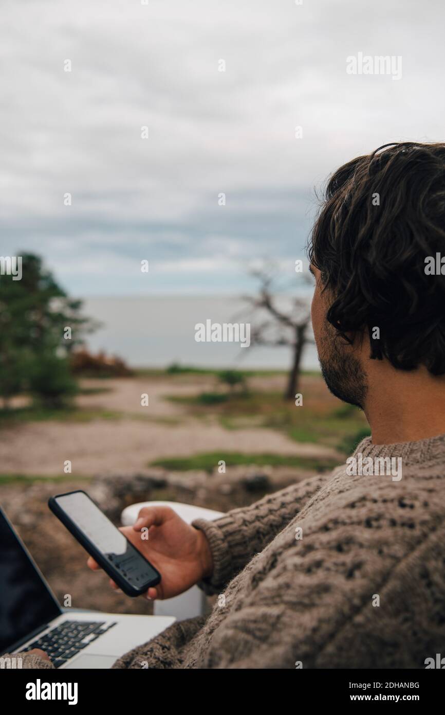 Primo piano di un uomo con messaggi di testo sul computer portatile mentre guardare fuori Foto Stock