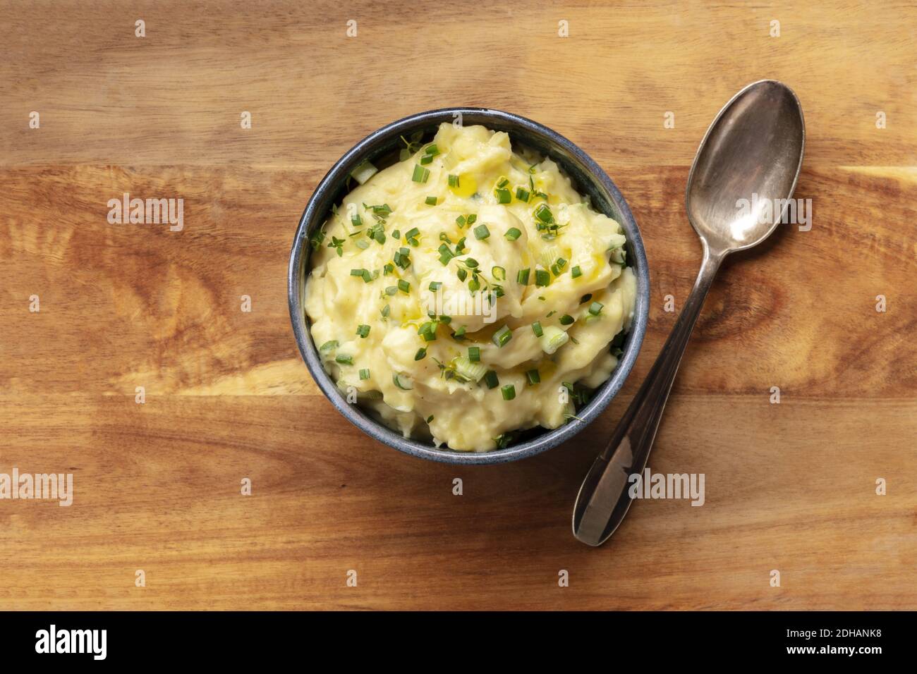 Purea di Pomme, una foto in alto di una ciotola di purè di patate con erbe, sparata dall'alto su uno sfondo rustico Foto Stock