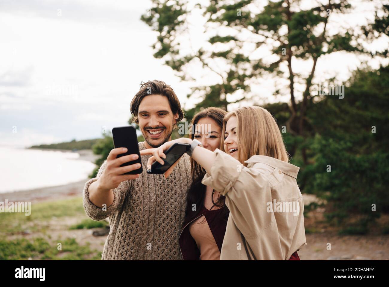 Amici felici che prendono selfie su smartphone in spiaggia Foto Stock