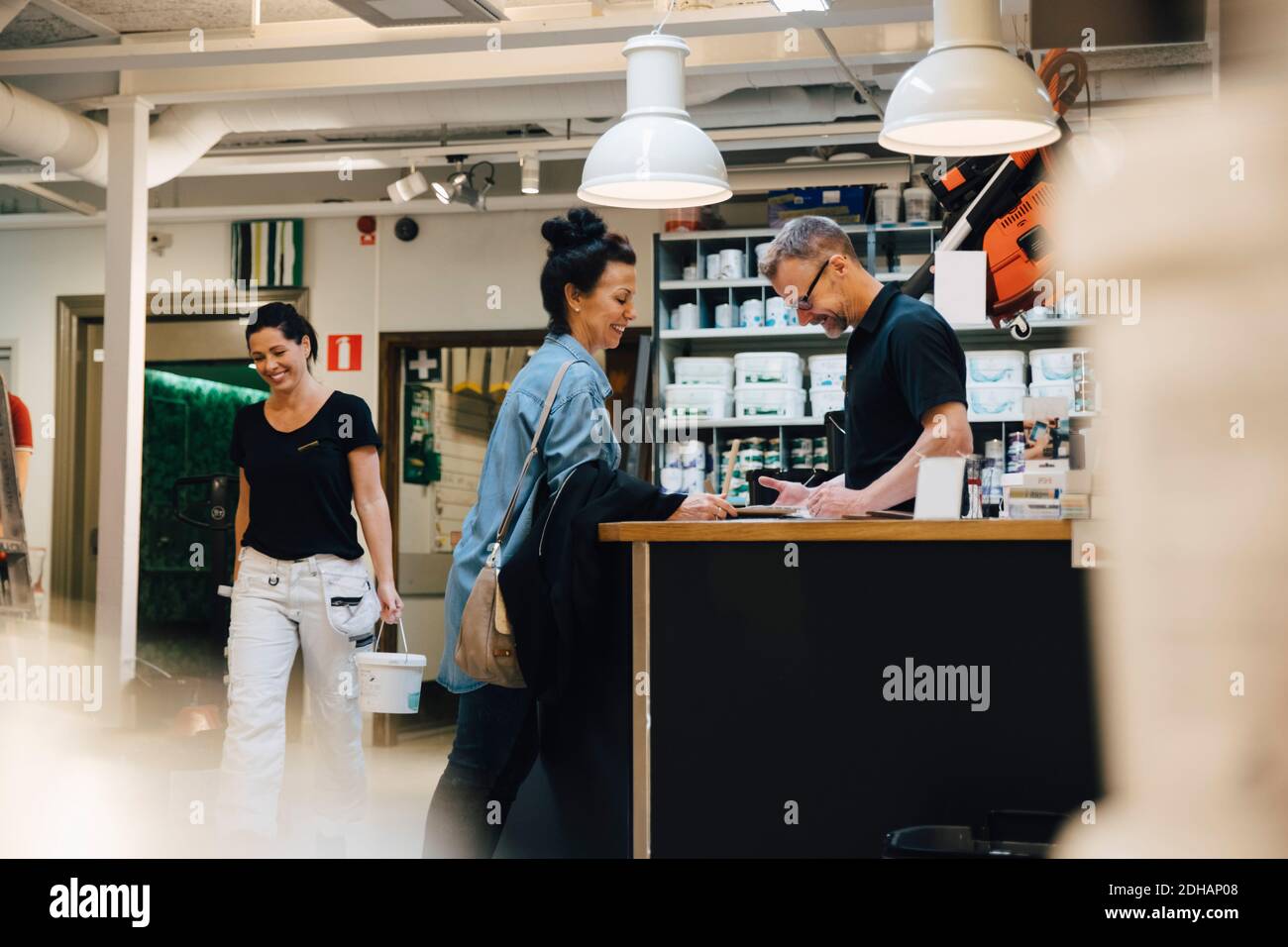 Sorridente venditore che assiste il cliente presso il negozio di hardware Foto Stock