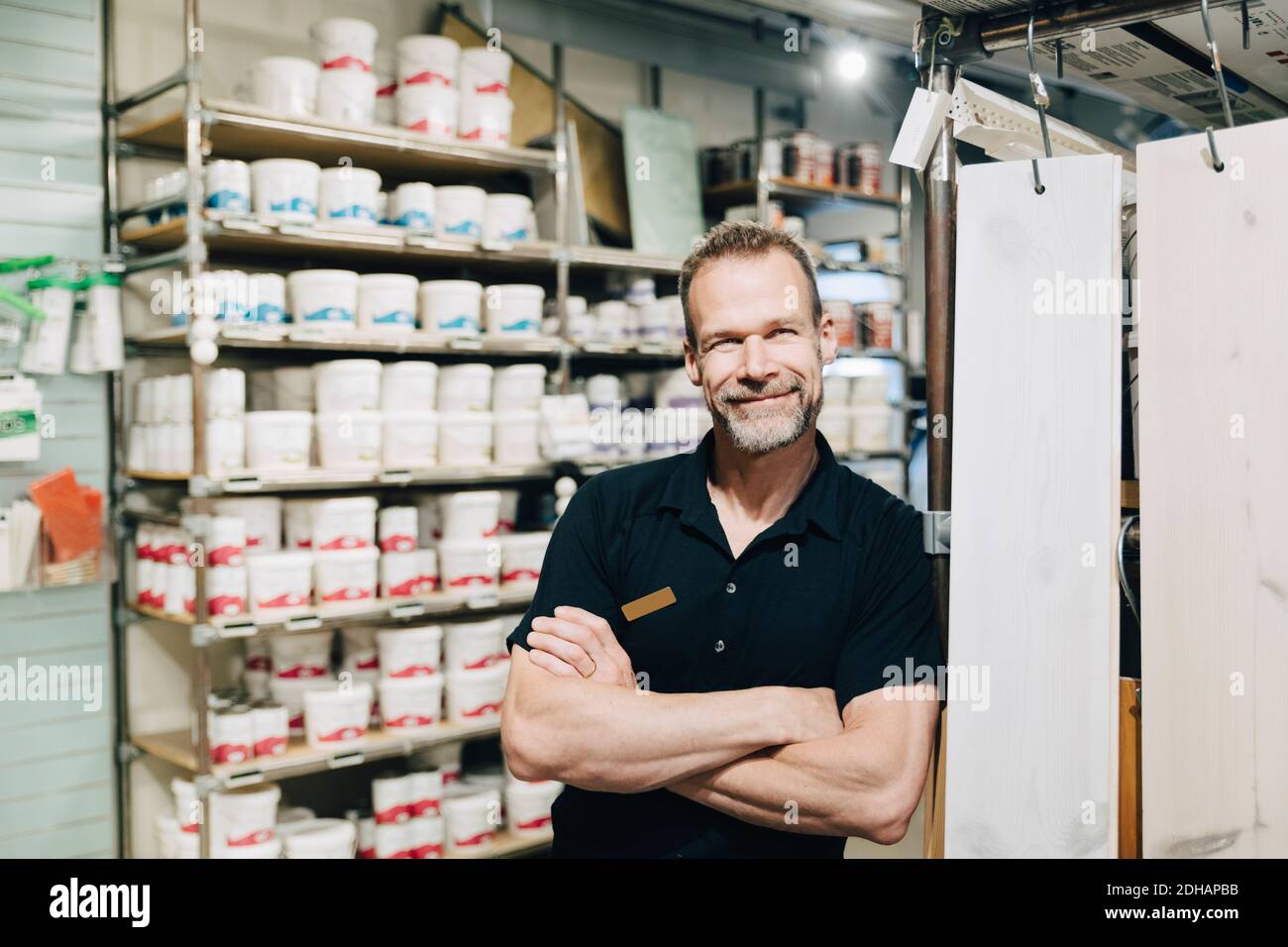 Ritratto di un venditore sorridente con braccia incrociate in piedi in negozio Foto Stock