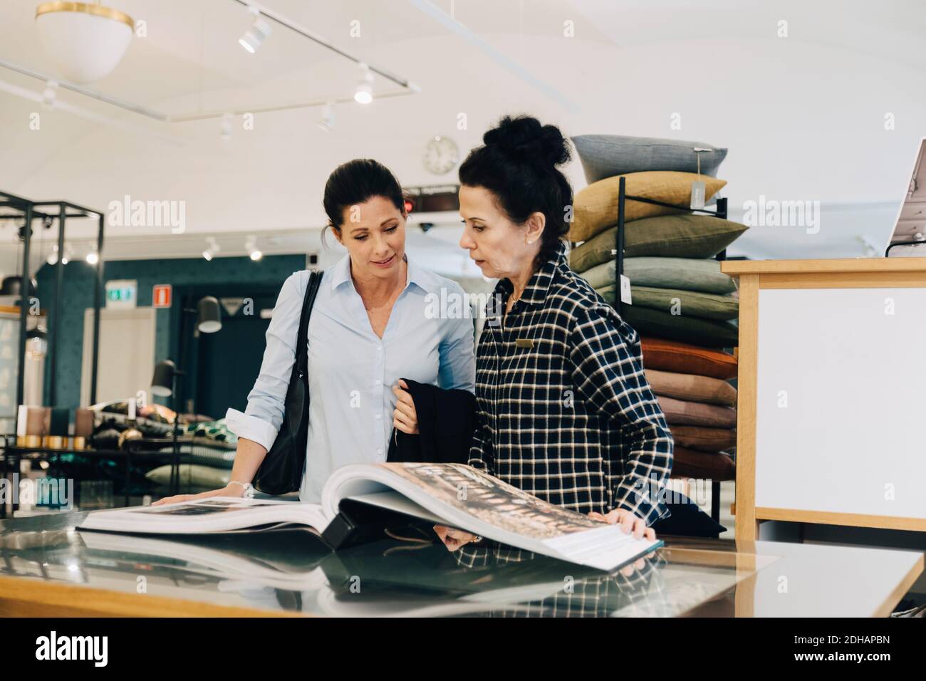Donna che assiste il cliente nella scelta del campione di carta da parati in negozio Foto Stock