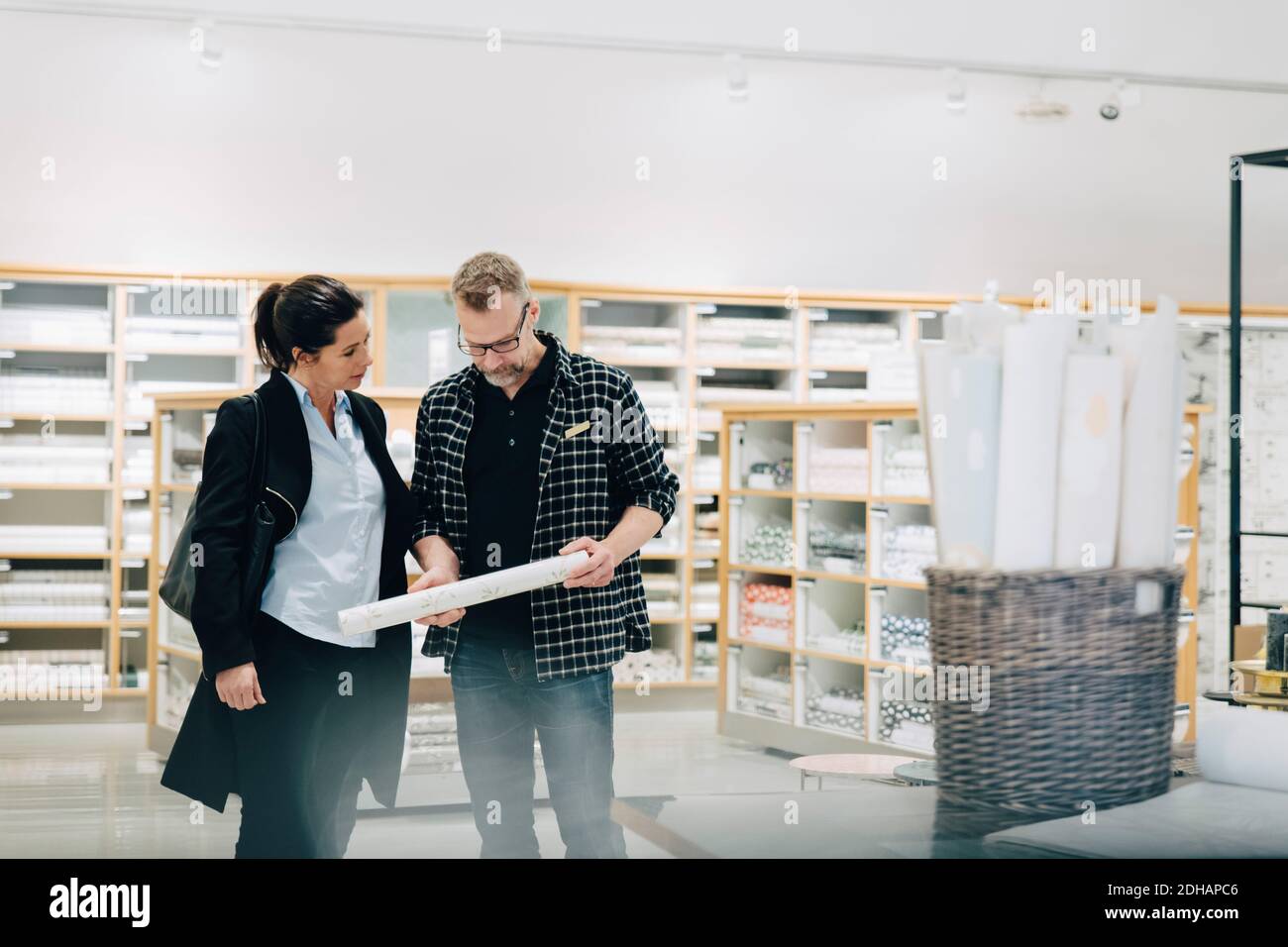 Venditore che mostra lo sfondo al cliente femminile in negozio Foto Stock
