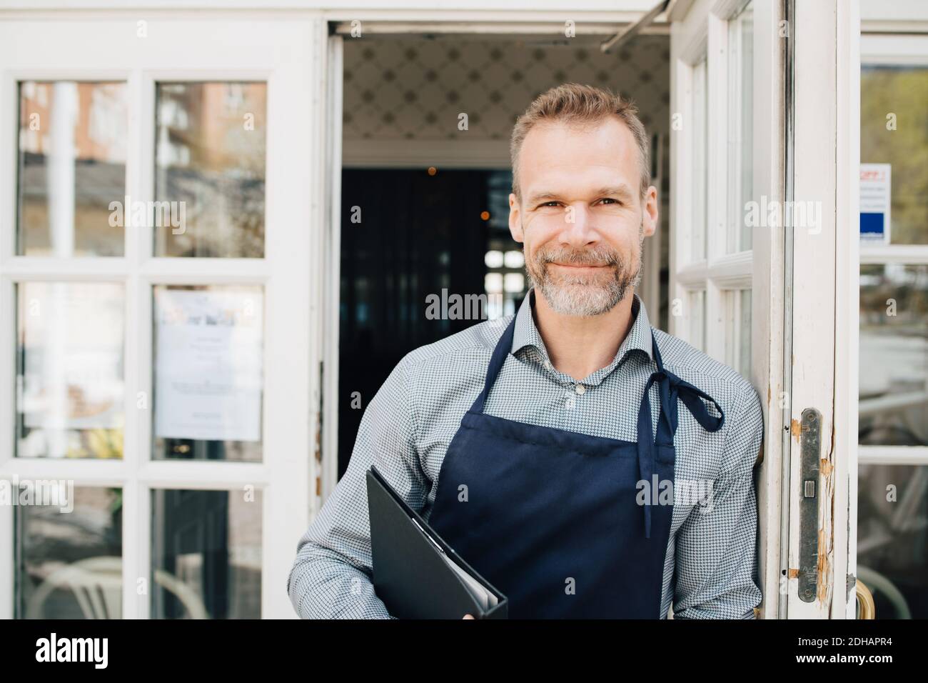 Ritratto del proprietario del ristorante in piedi accanto alla porta Foto Stock