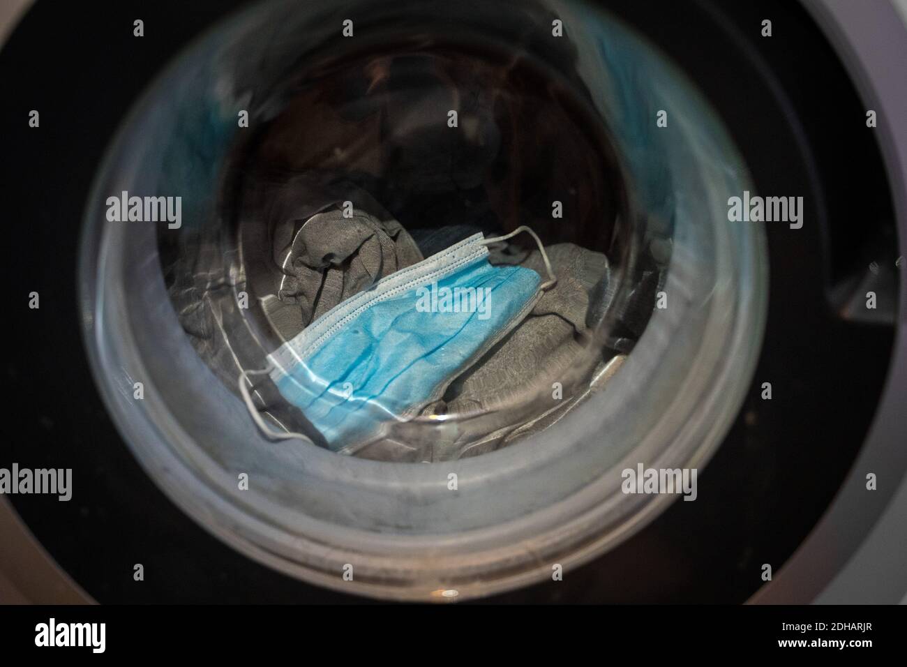 Una maschera chirurgica viene lavata in una lavatrice. Foto Stock