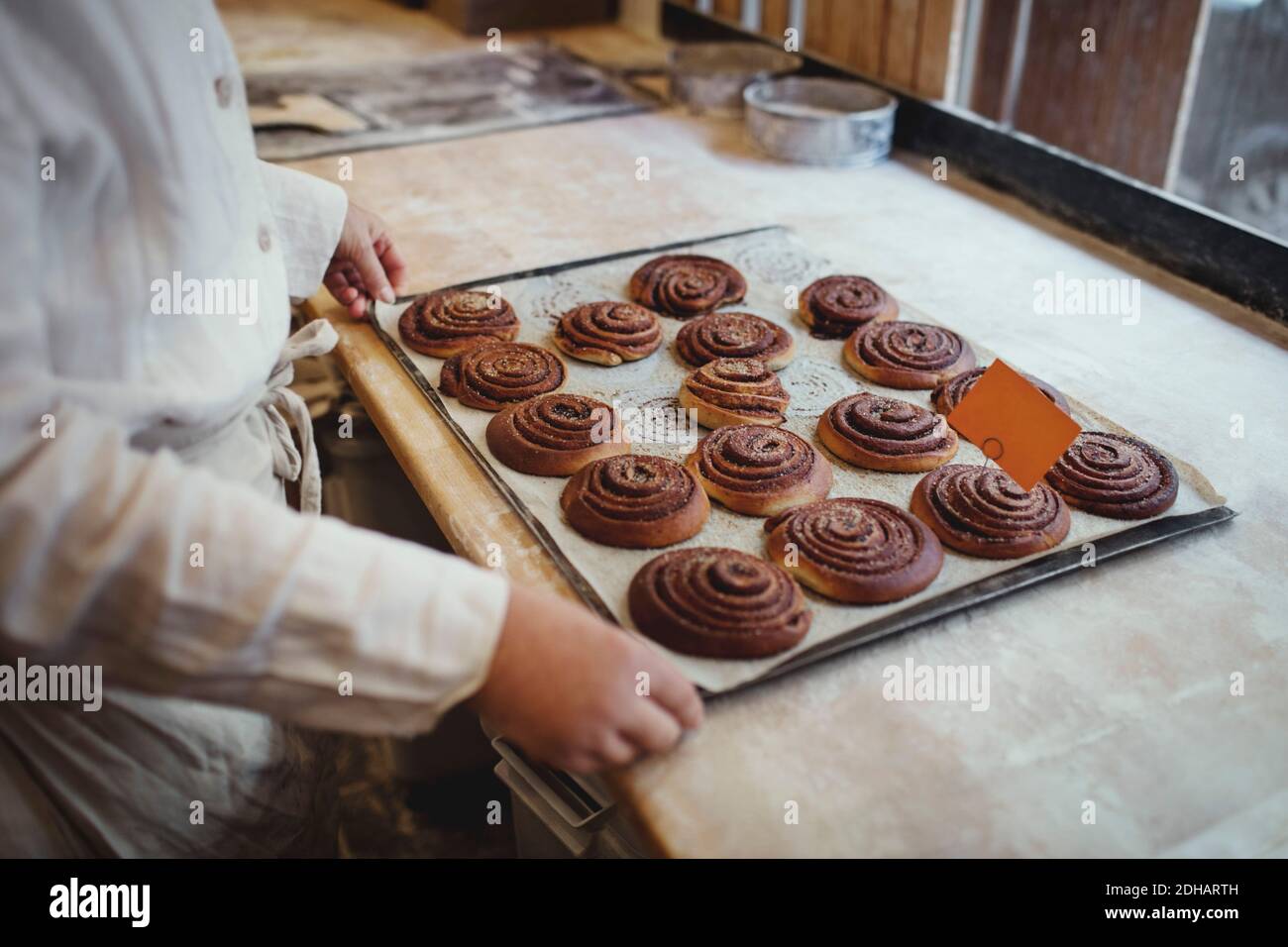 Sezione centrale del panettiere femminile con cibi dolci cotti in vassoio sul tavolo Foto Stock