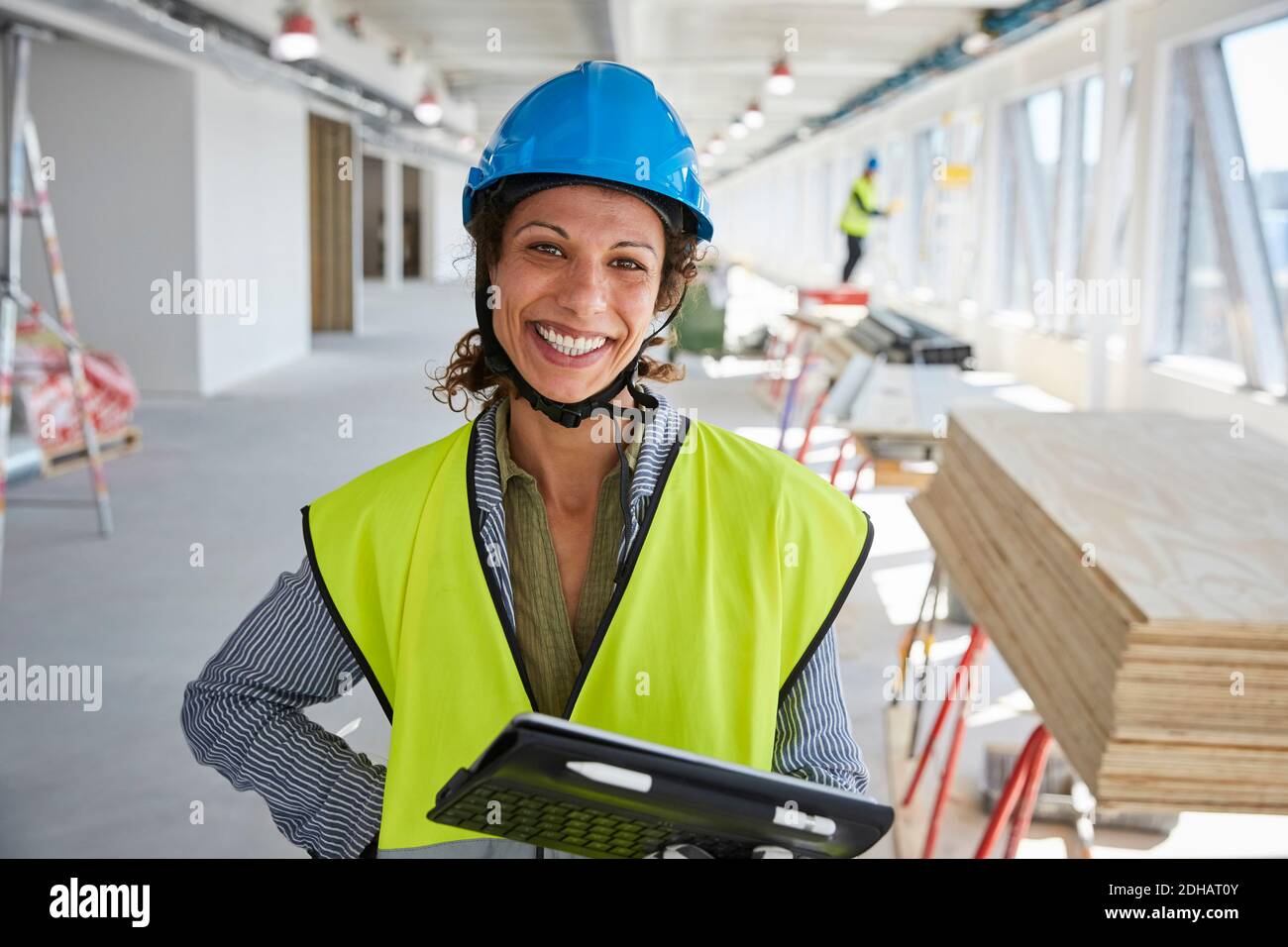 Ritratto di sorridente ingegnere femminile con tablet digitale in piedi cantiere Foto Stock