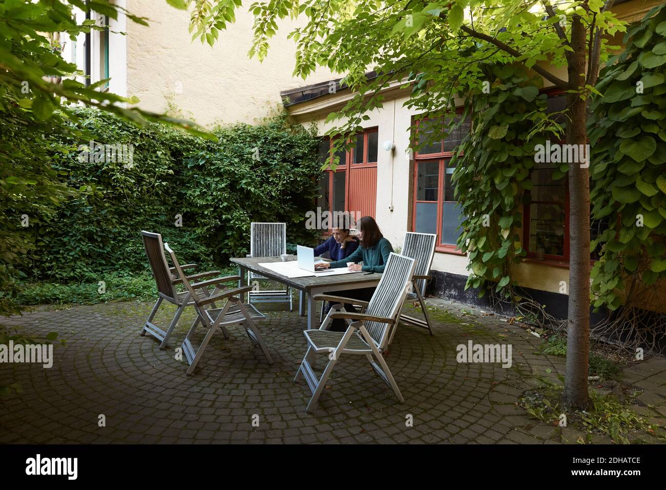 Architetti femminili che progettano su laptop al tavolo in cortile Foto Stock