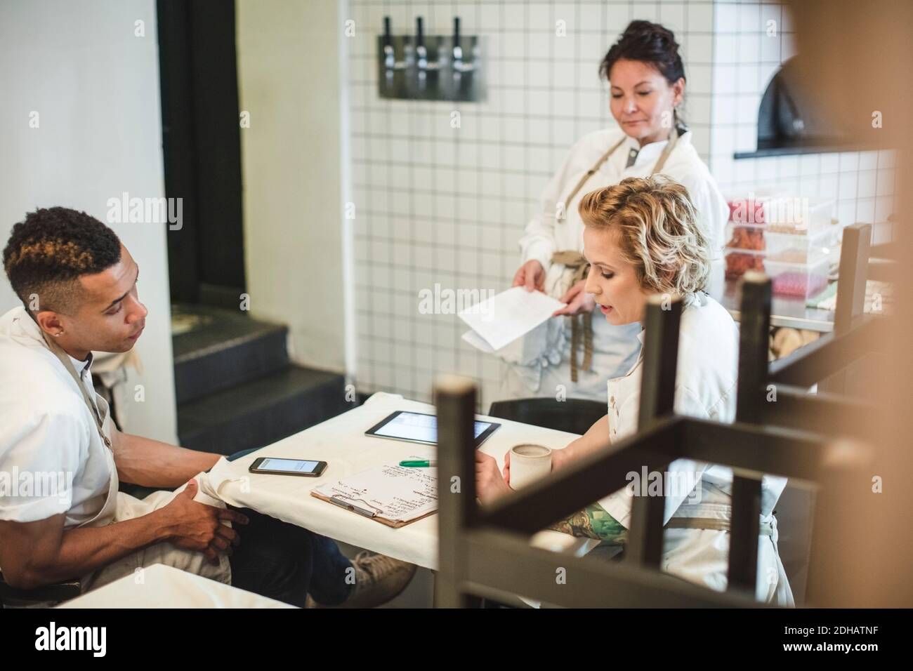 Vista ad alto angolo dei proprietari multietnici che discutono mentre si siedono a. tavolo nel ristorante Foto Stock