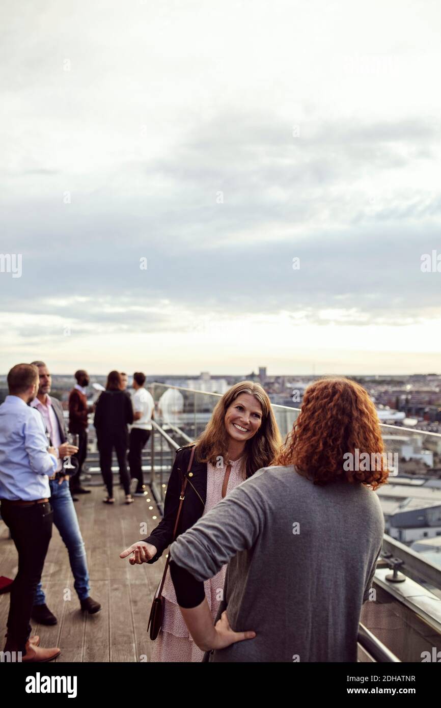 Sorridenti dirigenti aziendali che discutono sulla terrazza durante la festa in ufficio Foto Stock