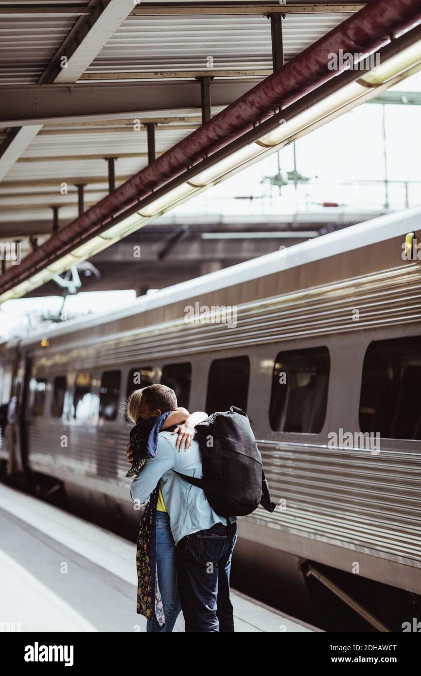 L'uomo e la donna si abbracciano mentre salutano in treno sulla ferrovia piattaforma della stazione Foto Stock