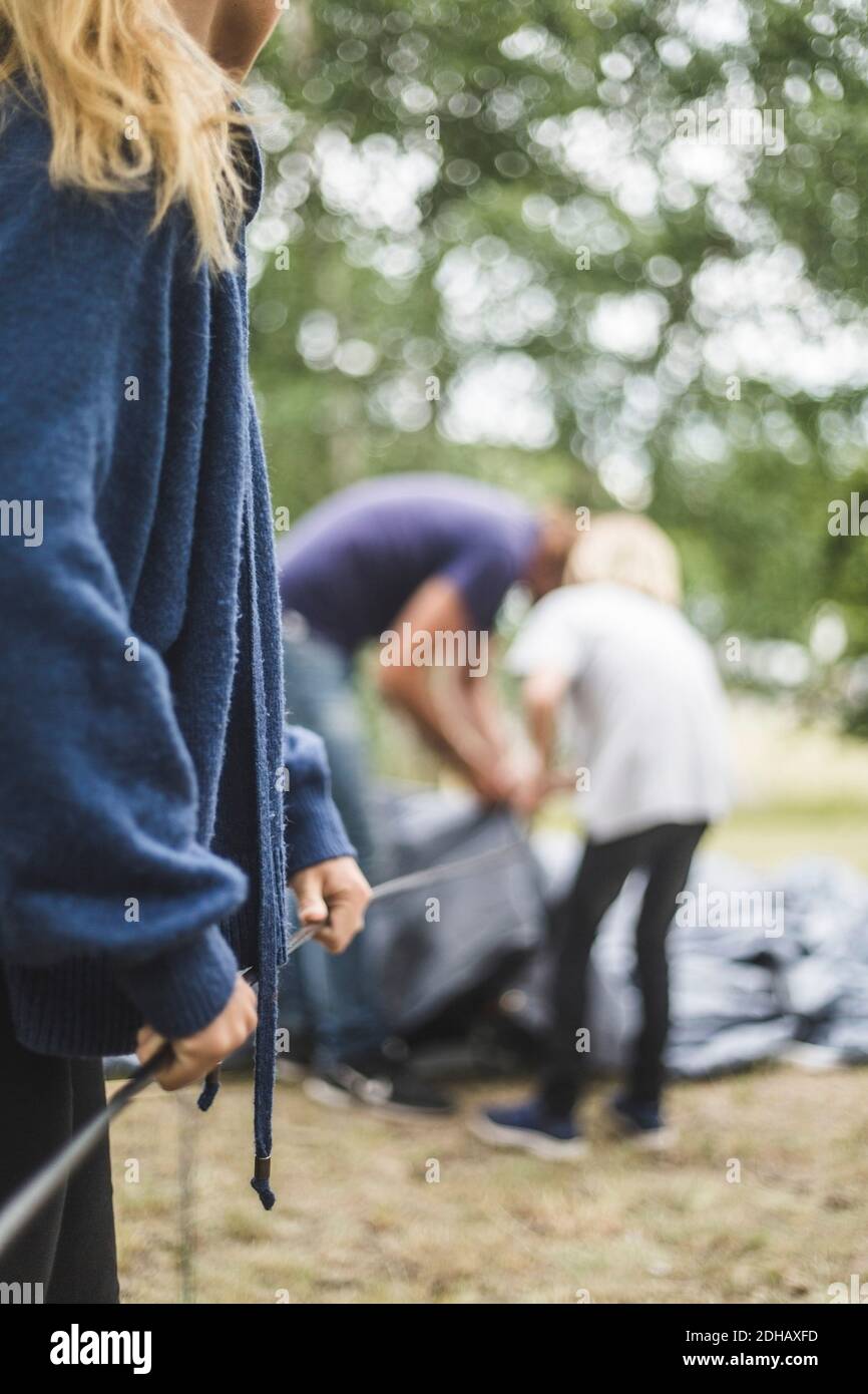 Metà sezione della ragazza teenage che assiste la famiglia in tenda di pitching a. campeggio Foto Stock