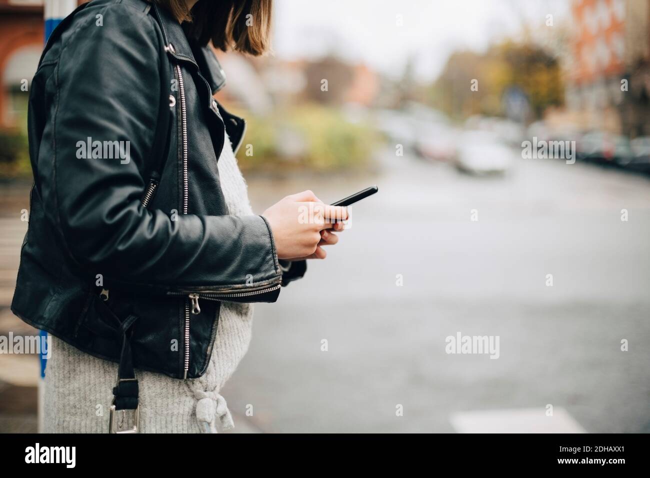 Mezza sezione di ragazza che usa il telefono cellulare mentre si trova in città via Foto Stock