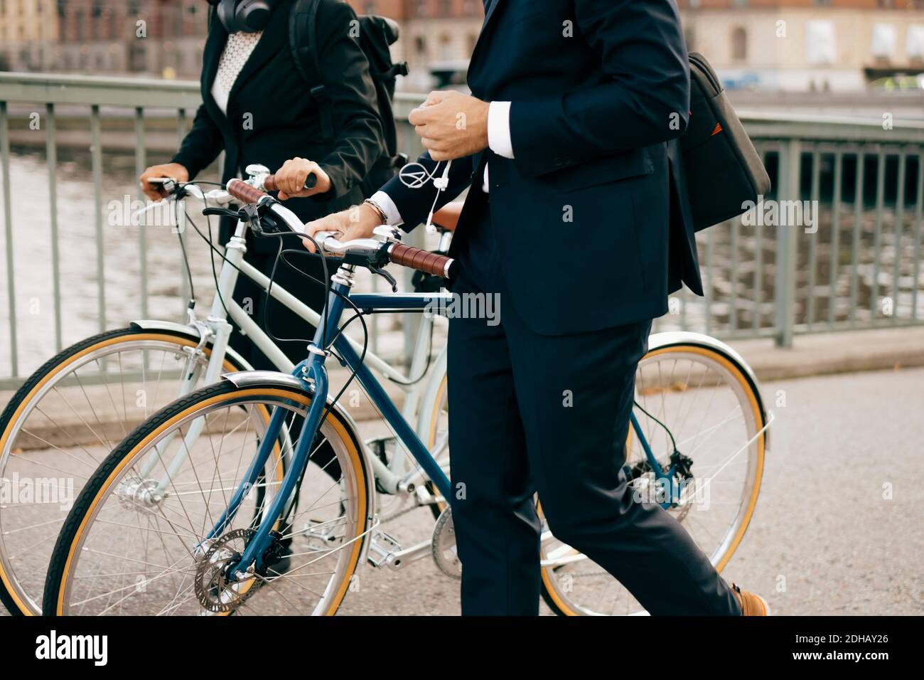 A metà strada tra uomo d'affari e uomo d'affari che cammina con le biciclette sul ponte in città Foto Stock