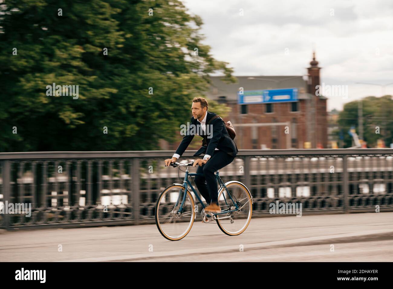 Tutta la lunghezza di un uomo d'affari sicuro che corre in bicicletta sulla strada della città Foto Stock