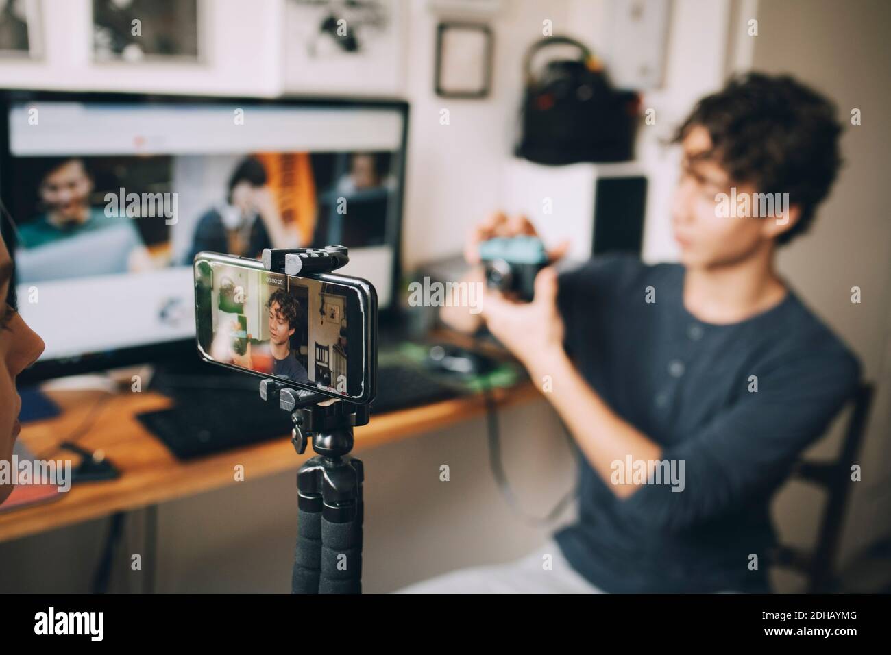 Ragazza che filma un amico sul telefono cellulare utilizzando la fotocamera mentre si è seduti a casa Foto Stock