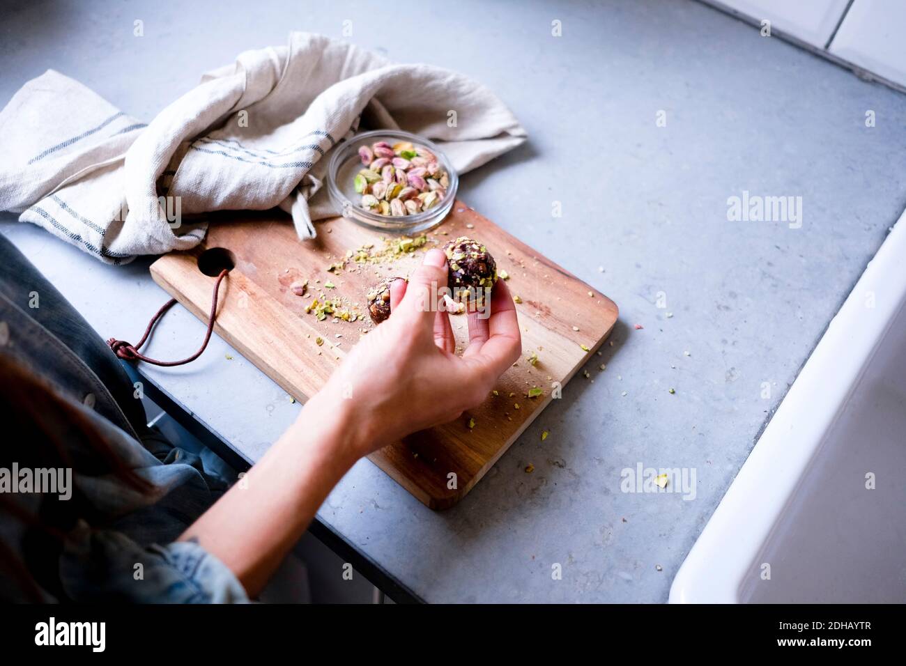 Immagine ritagliata di una donna che prepara tartufi al pistacchio di cioccolato in cucina contatore Foto Stock