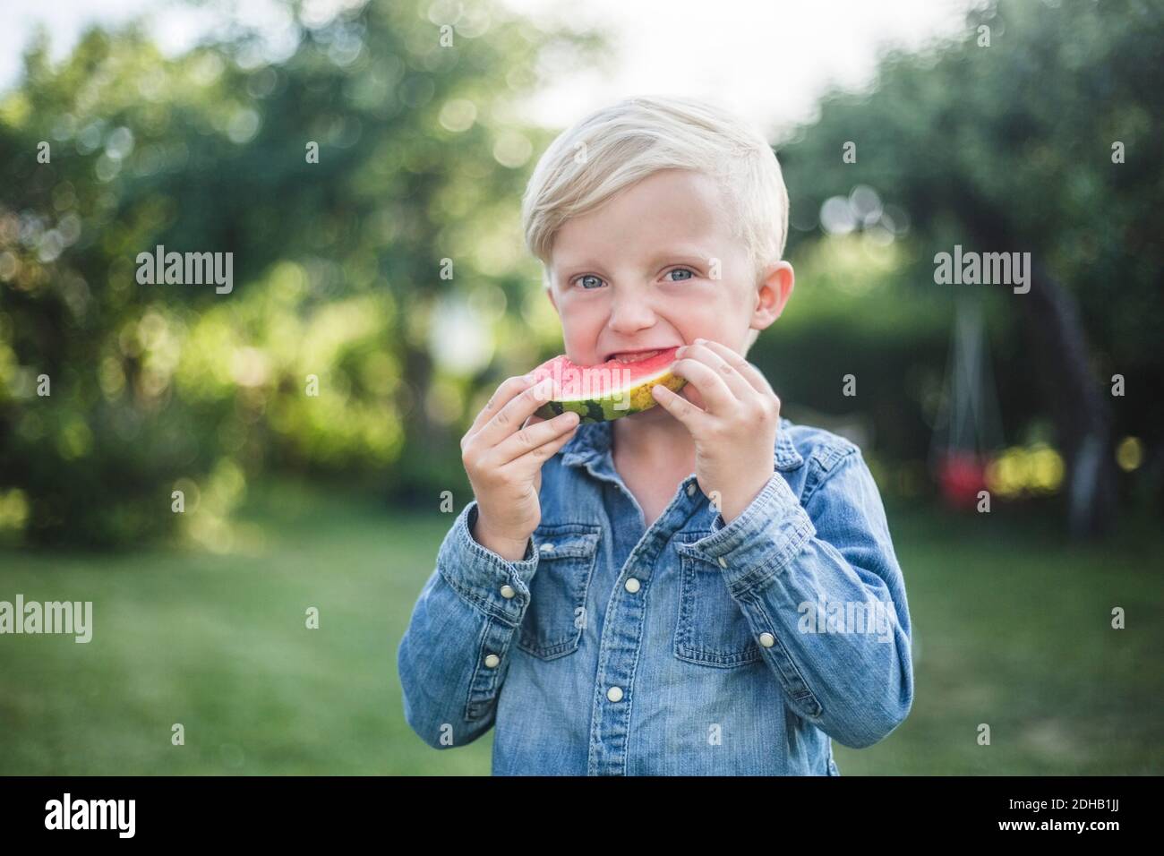 Ritratto di ragazzo che mangia cocomero fresco in cortile Foto Stock