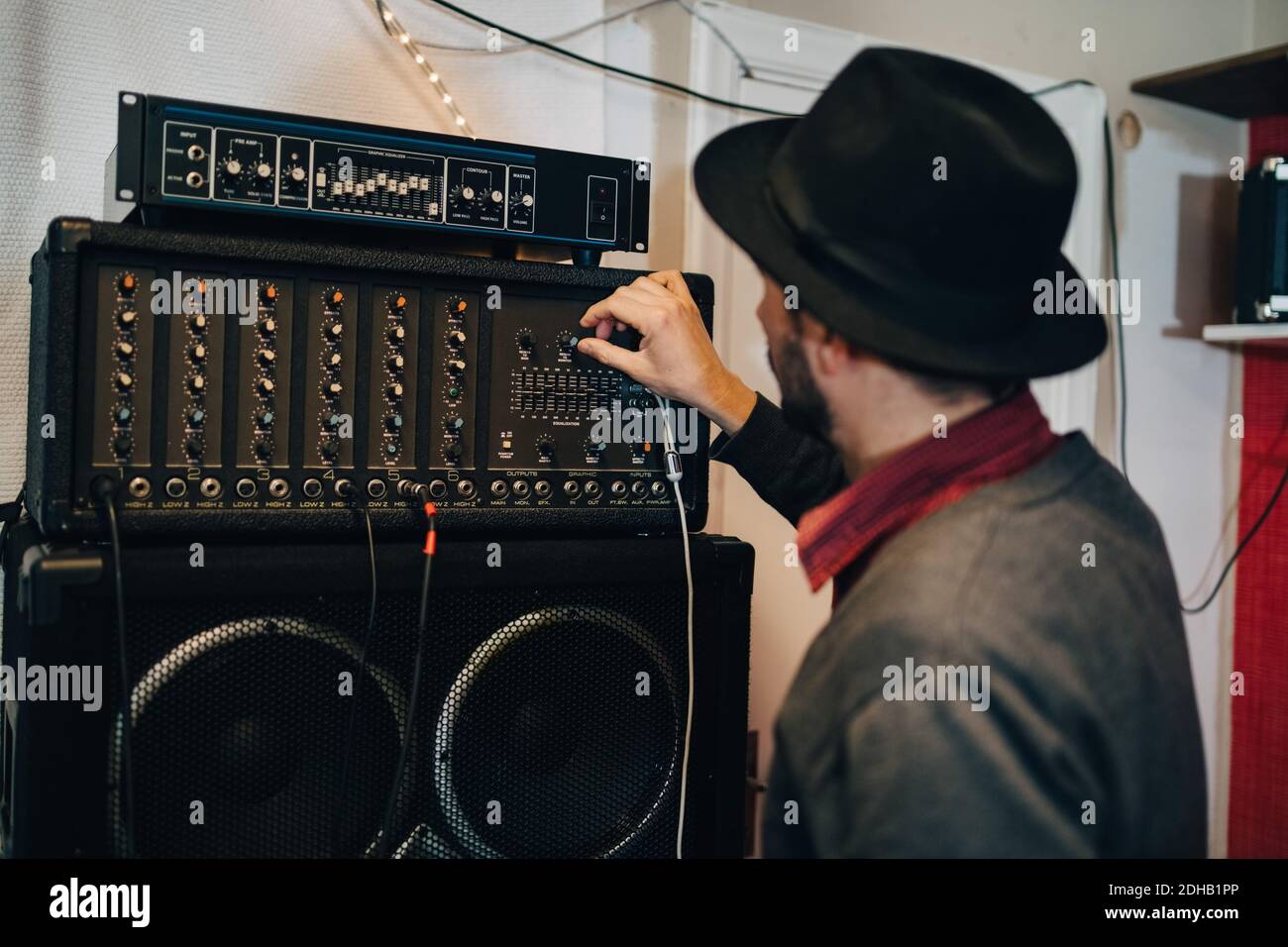 Uomo che regola l'apparecchiatura audio mentre si è in piedi allo studio di registrazione Foto Stock