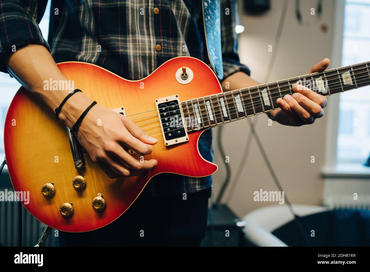 Sezione centrale dell'uomo che suona la chitarra mentre si prova in studio di registrazione Foto Stock