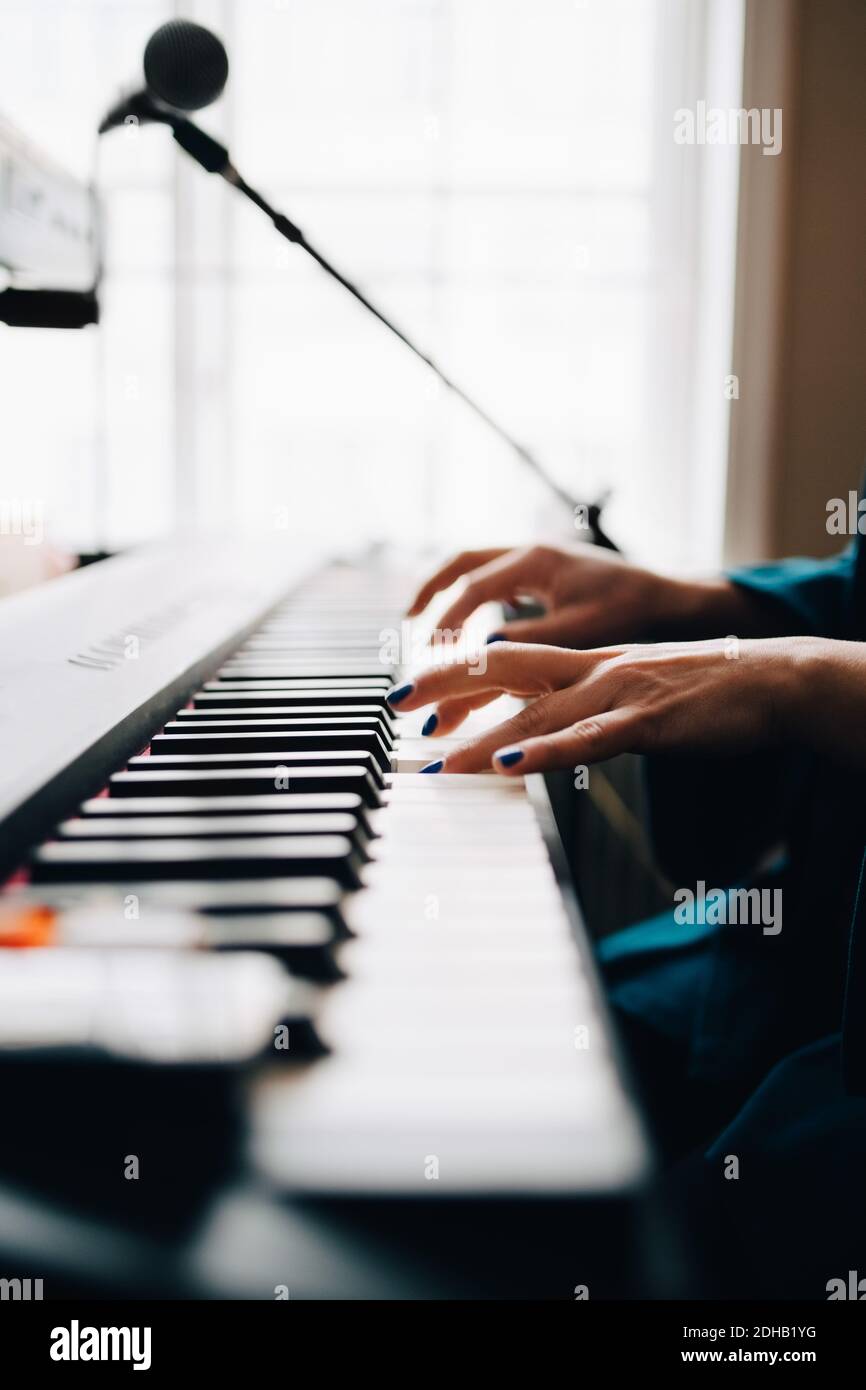 Immagine ritagliata di una donna che suona piano per finestra in studio Foto Stock