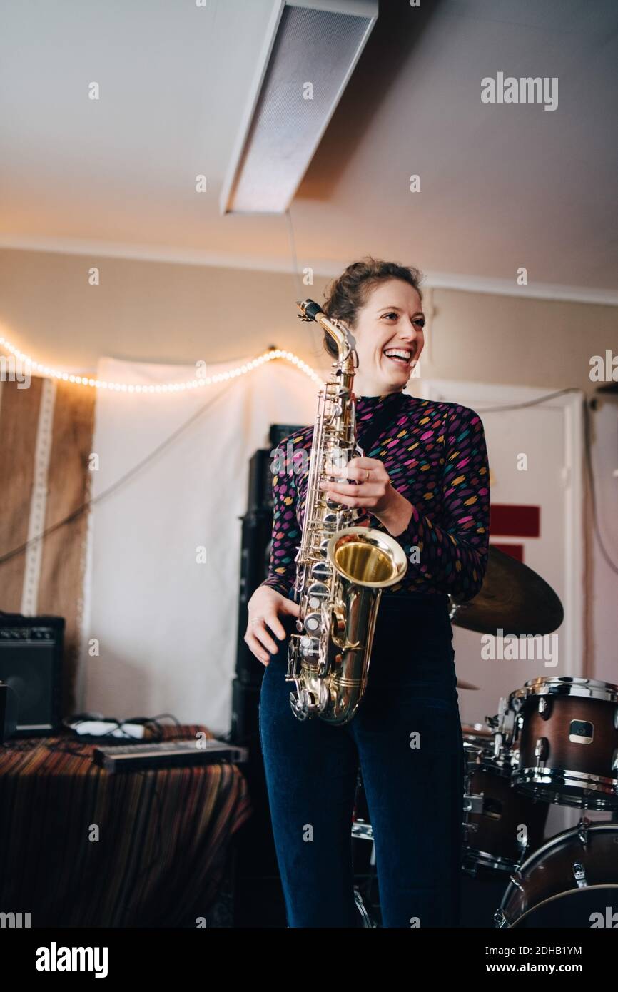 Felice giovane musicista che suona sassofono in studio di prove Foto Stock