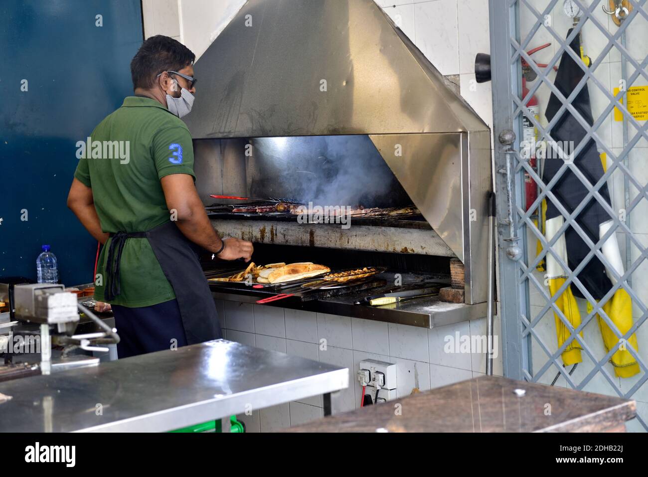 Chef tostatura pitta pane e carne di cottura su grill al carbone con cappa chimica sopra al ristorante Foto Stock