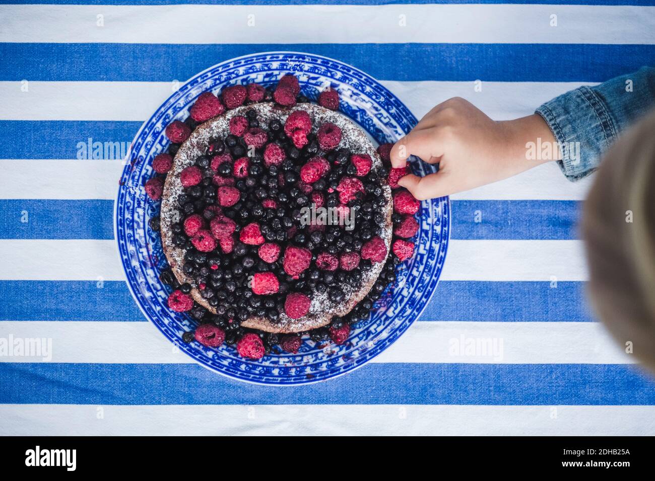 Direttamente sopra shot di ragazzo che raccoglie lampone in crostata a tavola Foto Stock