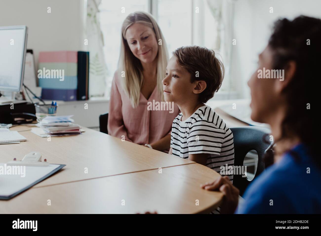 Madre e figlio consultano il medico con l'infermiera femminile alla scrivania in clinica Foto Stock