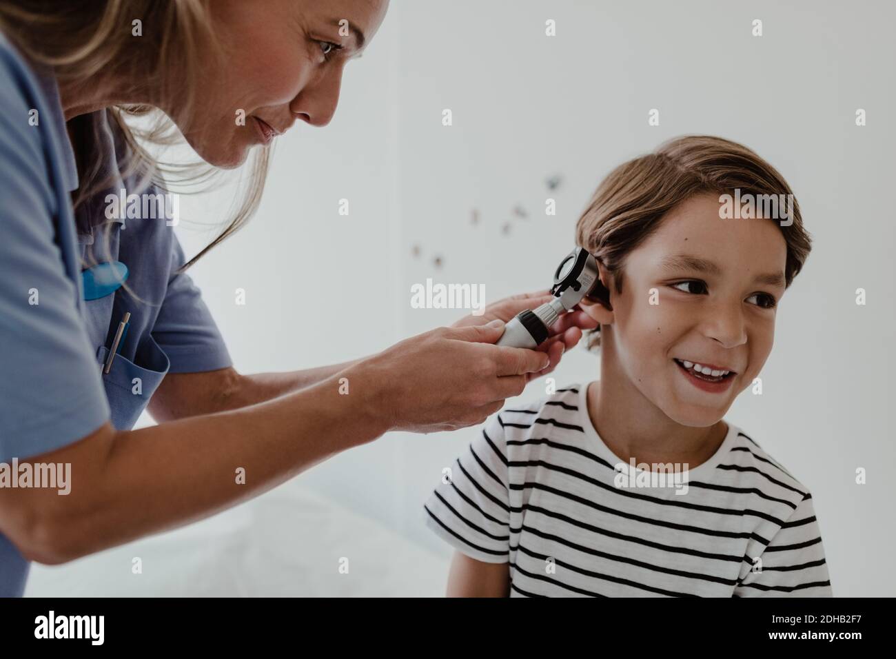 Medico che esamina l'orecchio del ragazzo con otoscopio in sala esame medico Foto Stock