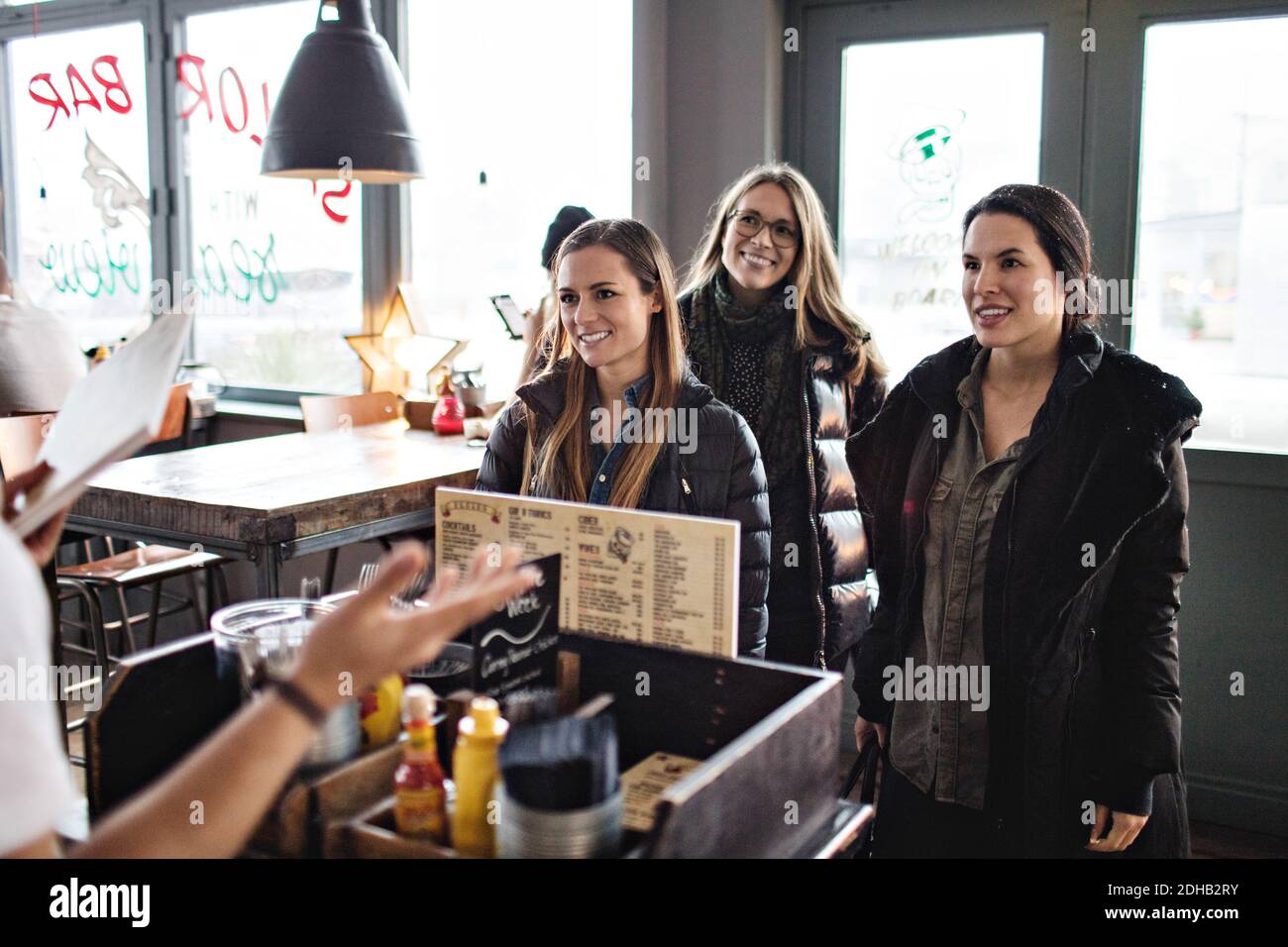 Sorridendo le amiche che guardano al proprietario del ristorante Foto Stock