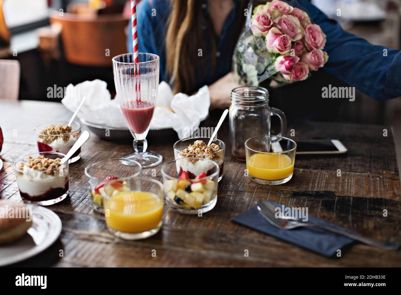 Metà della donna seduta con bouquet di fiori da cibo sopra tavolo da pranzo al ristorante Foto Stock