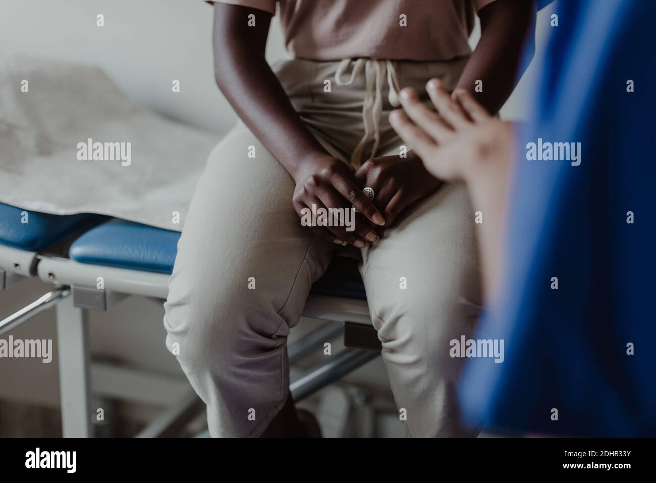 Sezione centrale dell'operatrice sanitaria femminile che spiega ai giovani pazienti dentro clinica medica Foto Stock