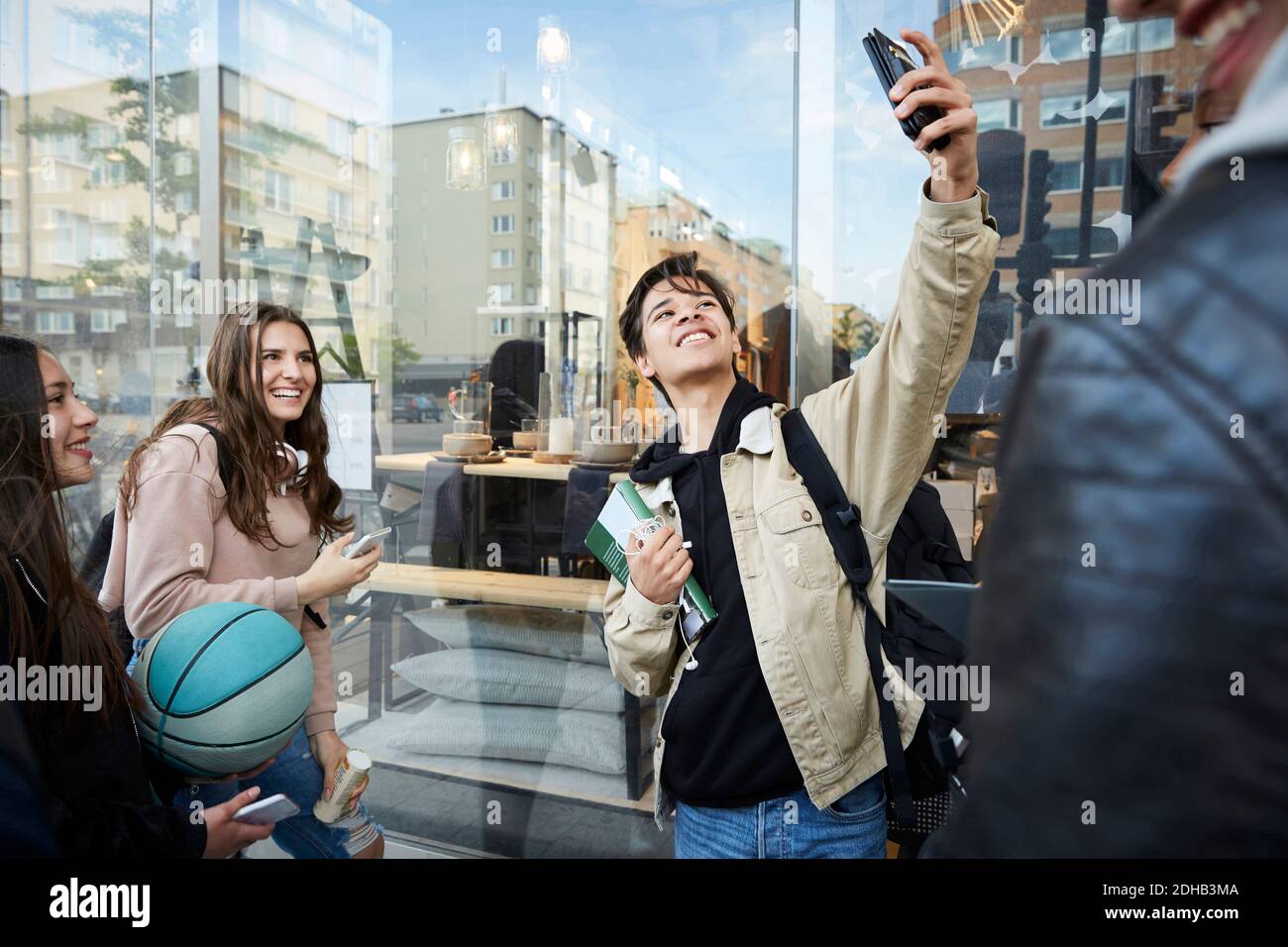 Sorridendo gli amici che prendono selfie mentre si levano in piedi in città Foto Stock