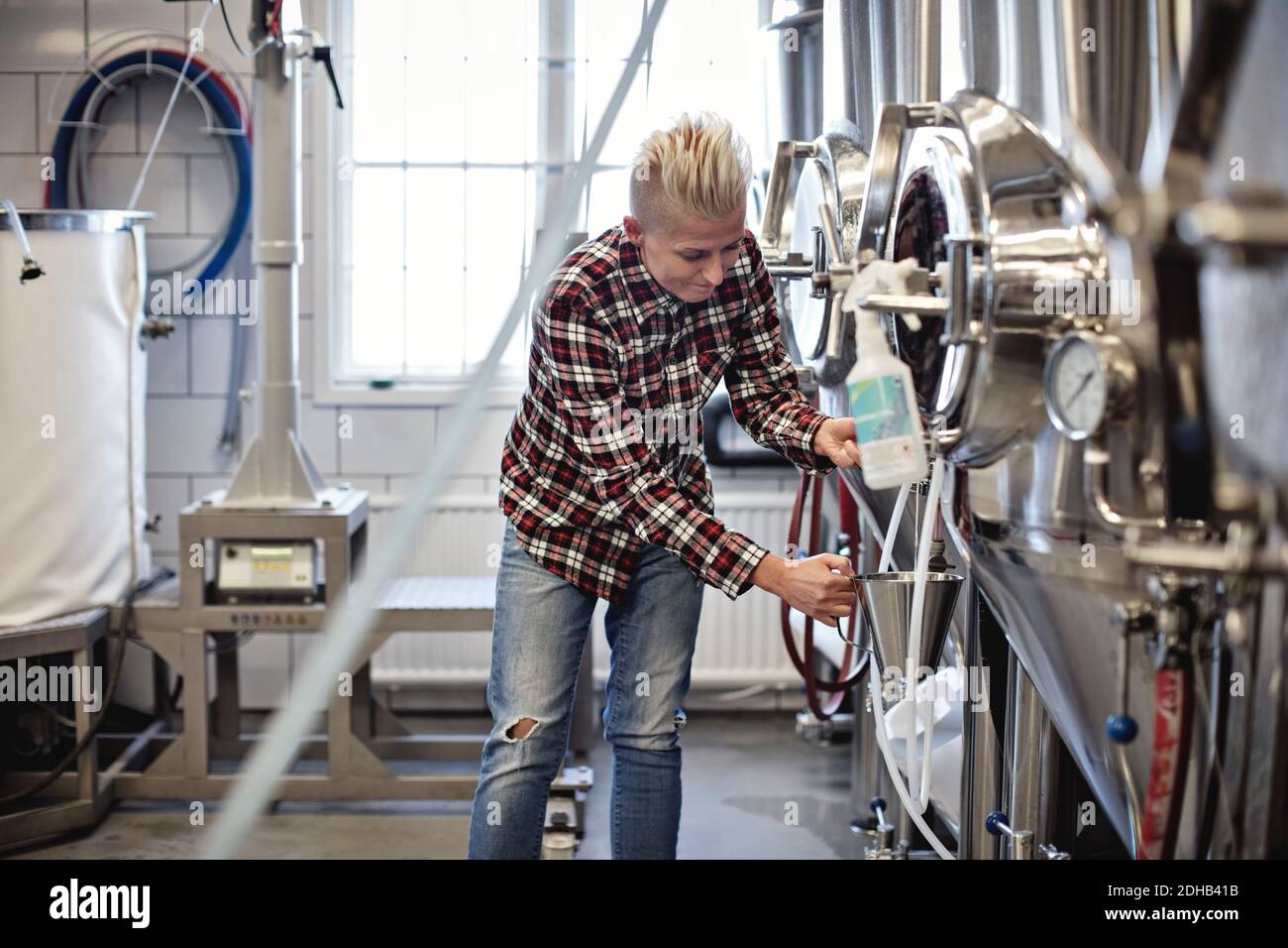 Responsabile femminile che lavora presso il serbatoio di stoccaggio presso la fabbrica di birra Foto Stock