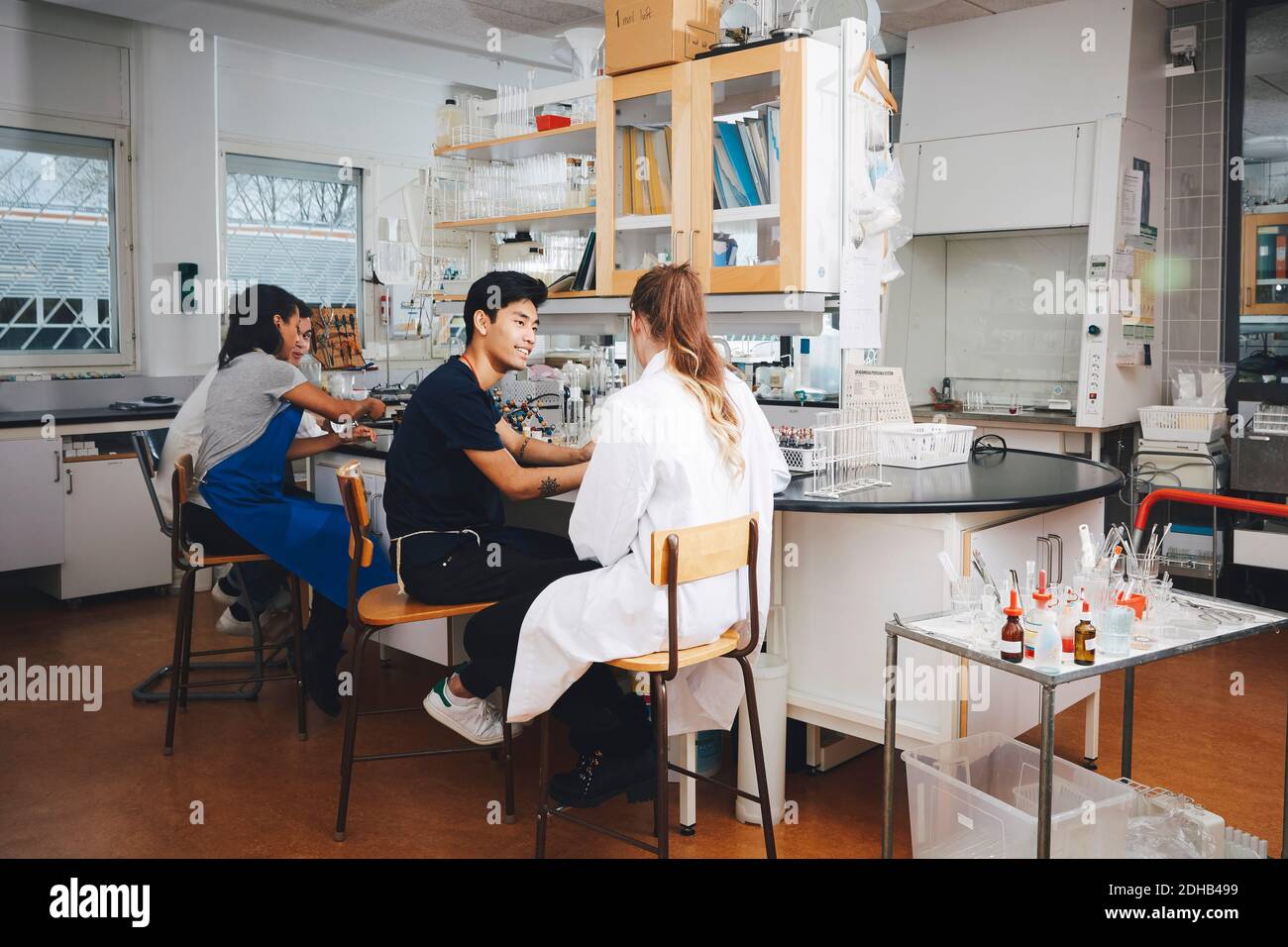 Giovani studenti universitari multietnici seduti su sedie in laboratorio di chimica Foto Stock