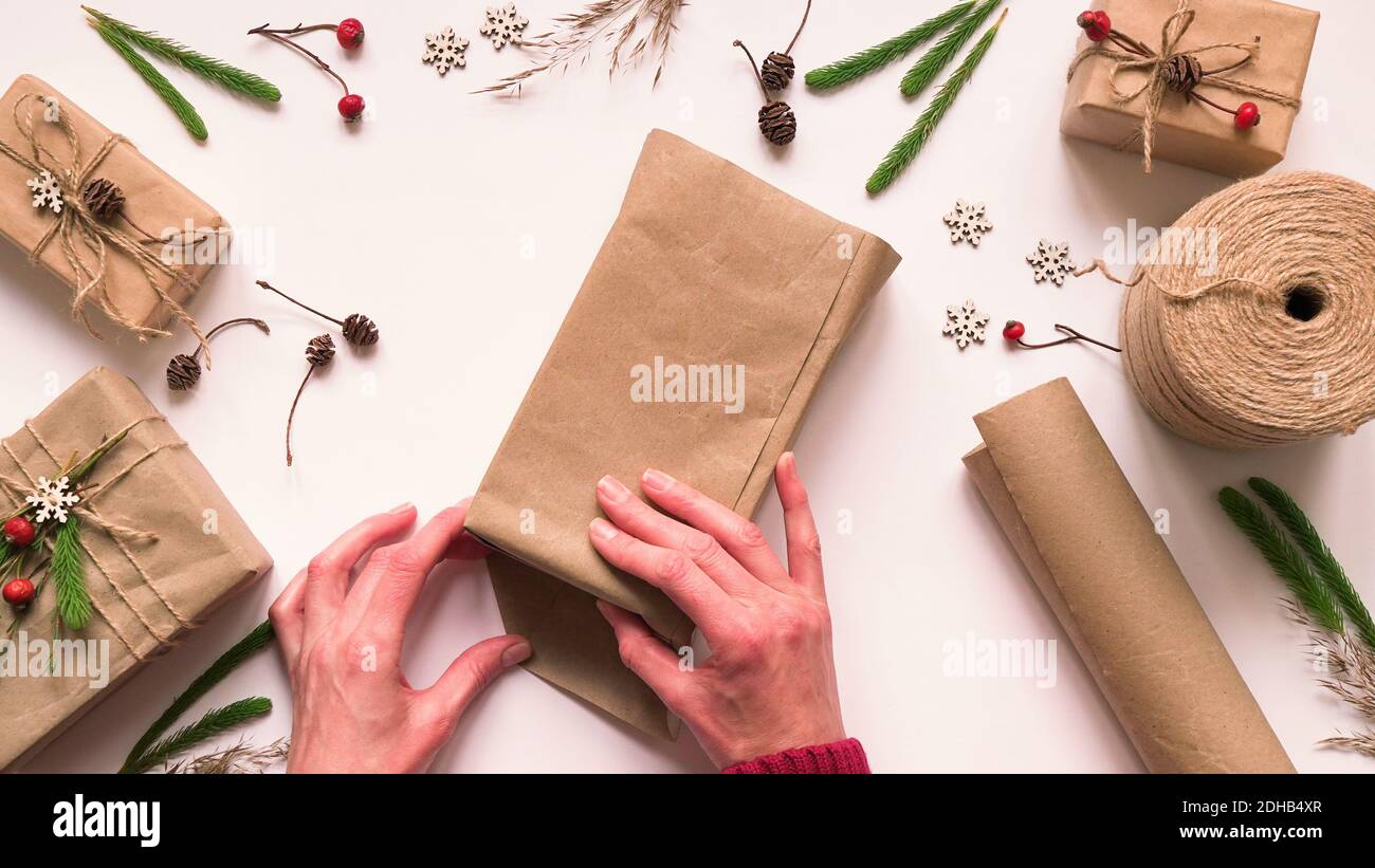 Passo 4. Passo dopo passo istruzioni per eco-friendly e zero Waste regalo wrapping.Woman wraps regalo in carta marrone e. sigilla i bordi con colla, v. superiore Foto Stock