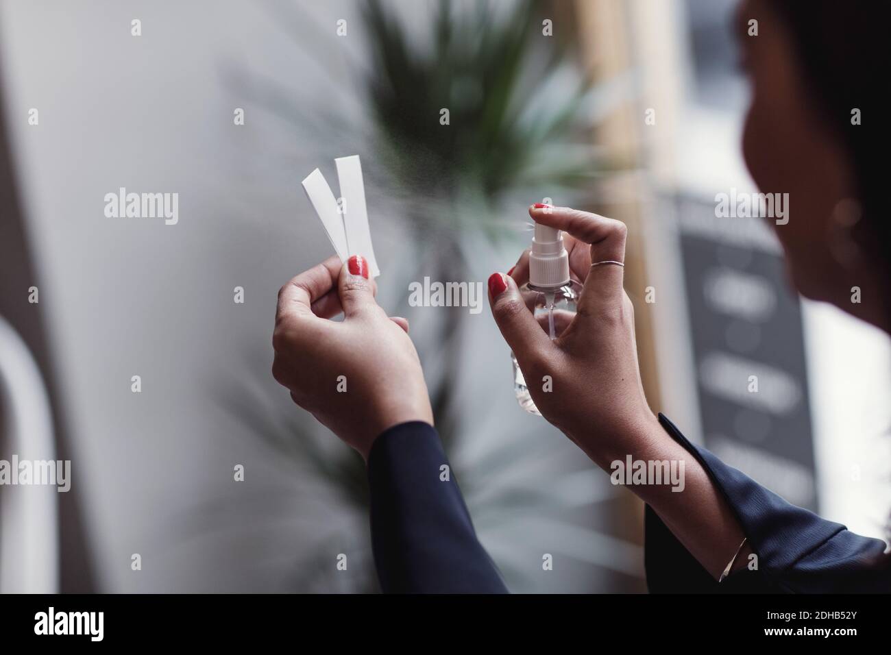 Immagine ritagliata di donna spruzzando profumo su strisce di tornasole a. officina Foto Stock