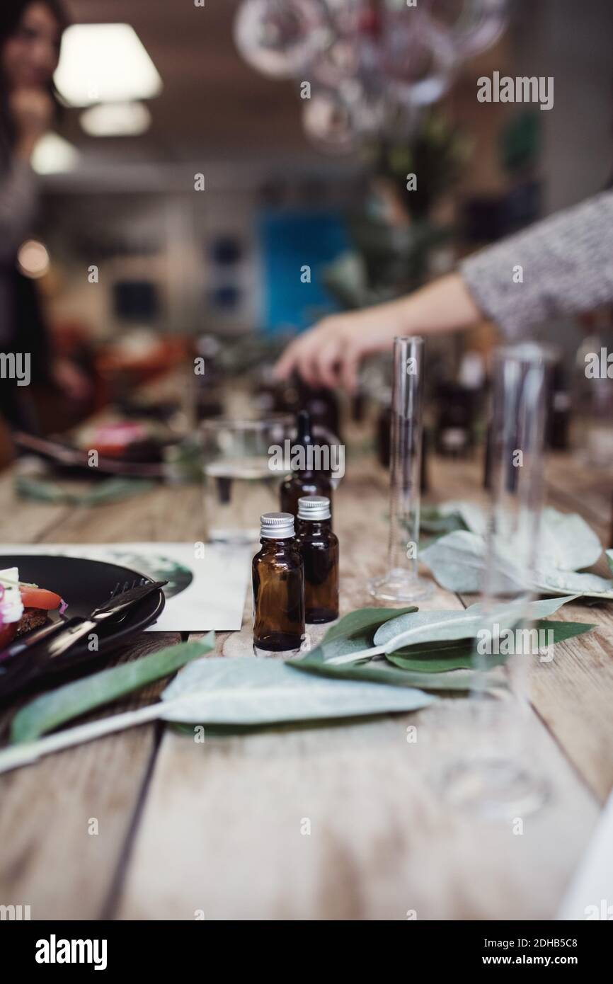 Bottiglie di profumo da foglie e piatto sul tavolo in officina Foto Stock